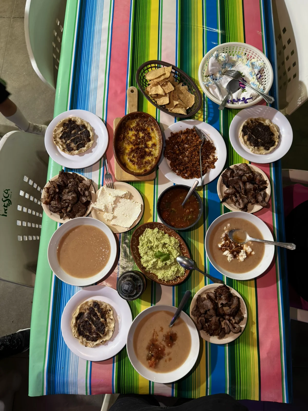 Mesa de La Curva con carne asada, queso fundido, frijoles, guacamole y tortillas hechas a mano